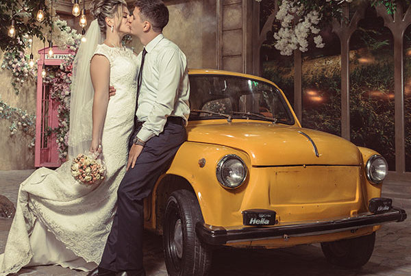 Just married couple share a kiss. yellow Fiat 500 in background.