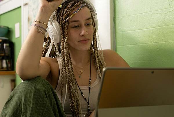 Millennial young woman with braids, sits at kitchen table with tablet and shops online, possibly for short term car insurance
