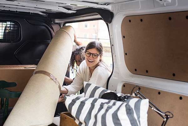 Two women spring cleaning by putting furniture into a van they have insured with temporary car insurance