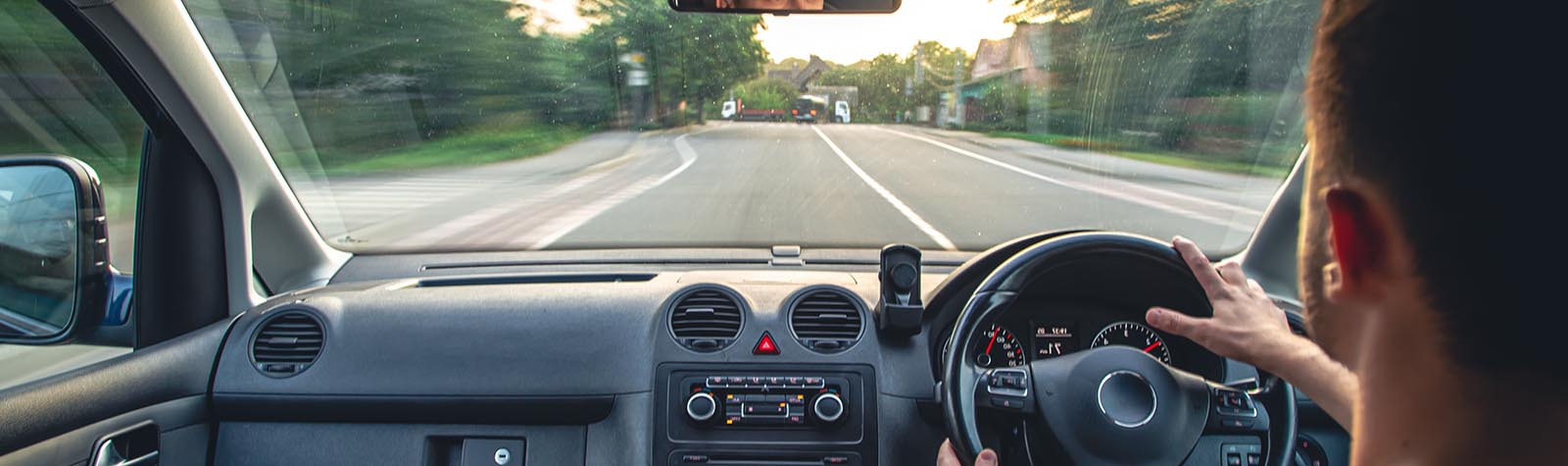 Man driving down city street. Point of view from behind his shoulder in the car.