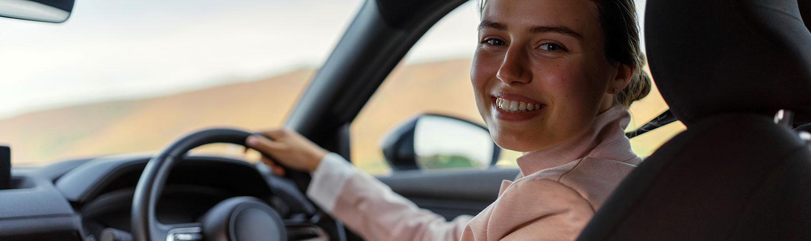 Young woman driver, smiling and looking back