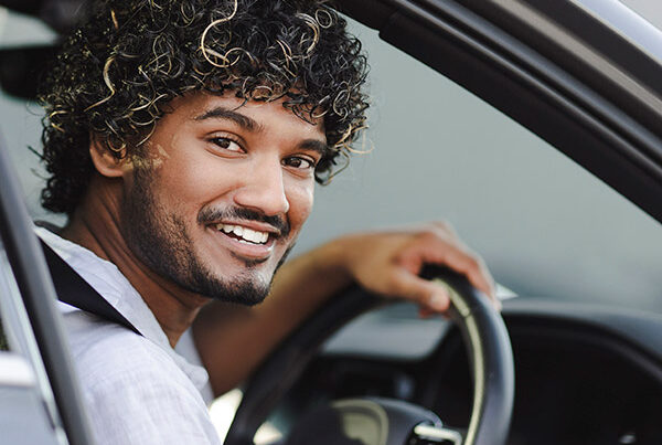 Young male driver, smiling and looking back through open door