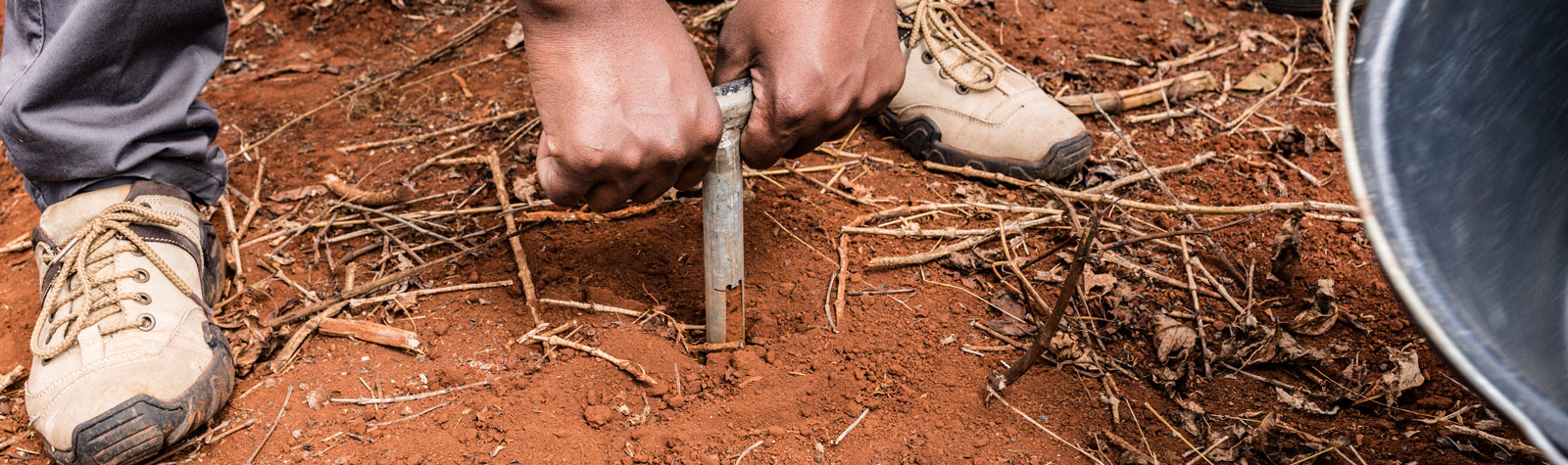 Black man's hands taking core sample of red earth Kenya