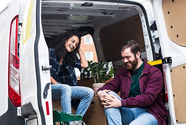 Young man and woman talk a break while moving furniture to van insured with temp cover