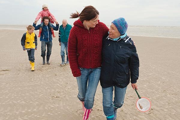 Multi-generational family walk on beach, made possible by day insurance