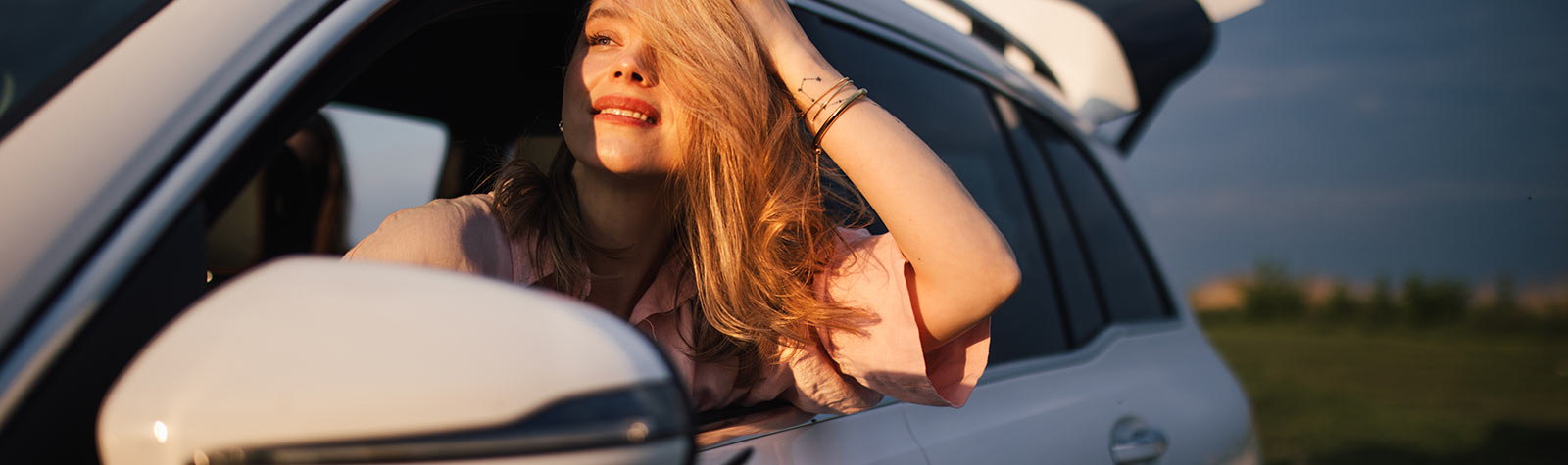 Happy young woman in passenger seat of white car